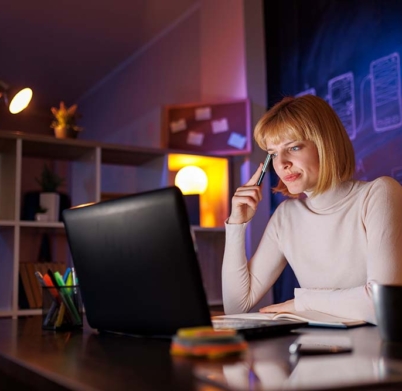 Woman sitting at her desk in home office, writing in planner while taking an online course