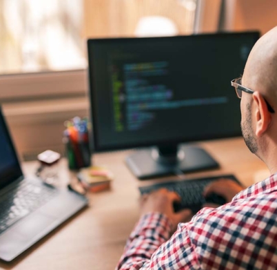 Male programmer working in home office, sitting at his desk and coding